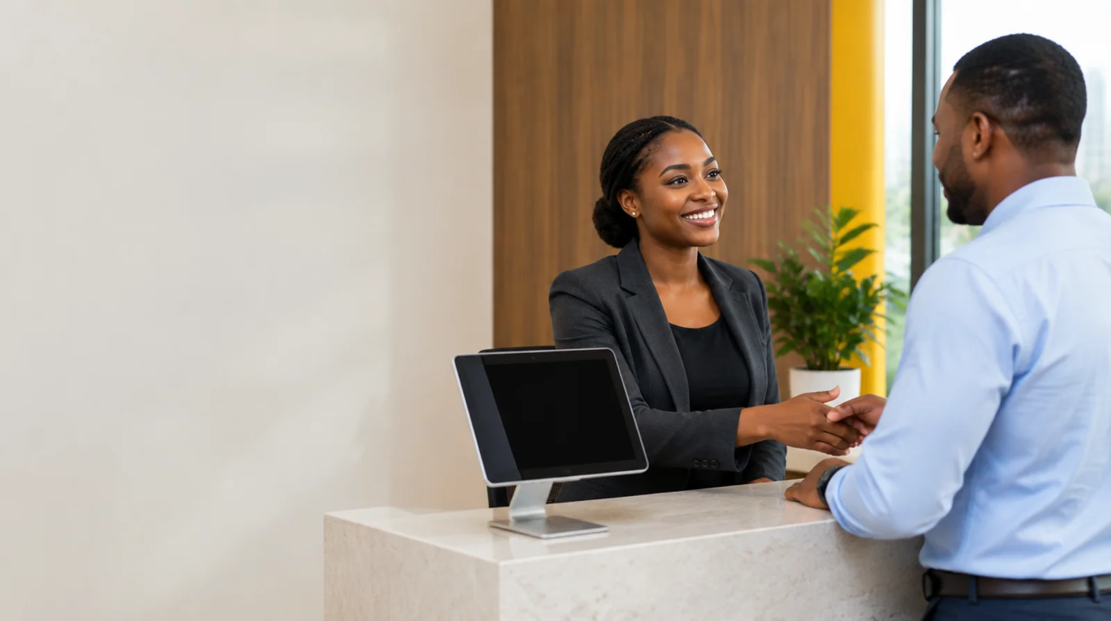 A receptionist warmly welcoming a visitor at a contemporary African workplace
